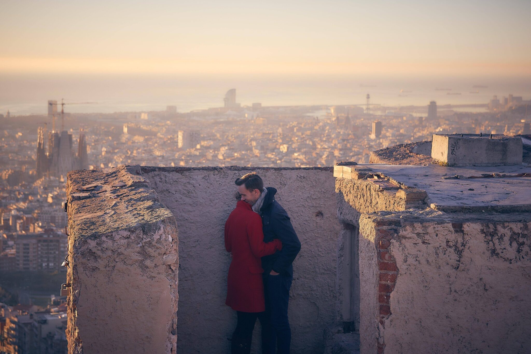 Pareja abrazada en su sesión preboda con vistas panorámicas de Barcelona al amanecer