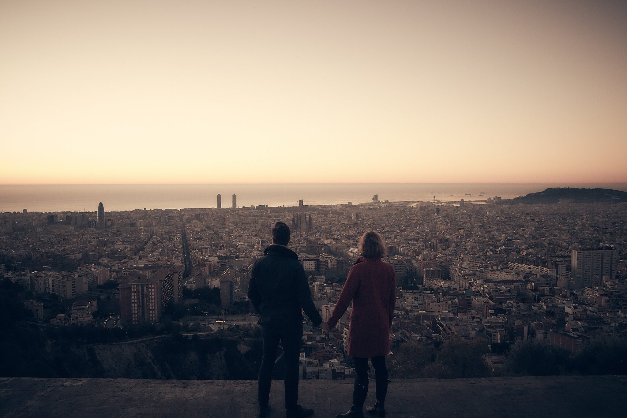 Pareja de novios en un mirador contemplando la silueta de la ciudad al atardecer.
