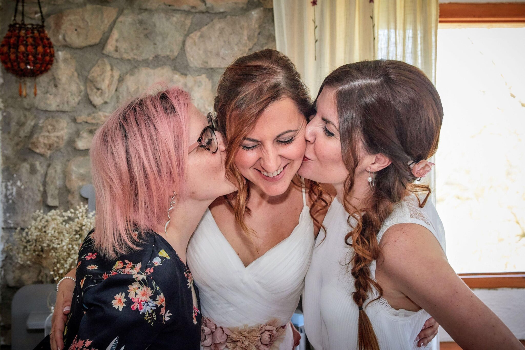Invitadas besando a la novia de forma espontánea en un reportaje documental de bodas.