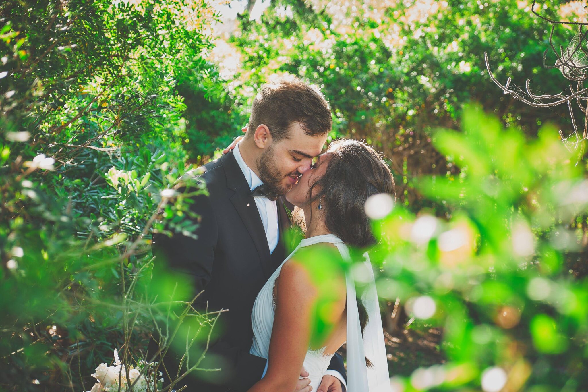 Beso natural y sin posados de una pareja rodeada de vegetación, capturado por un fotógrafo de boda en Barcelona con estilo documental